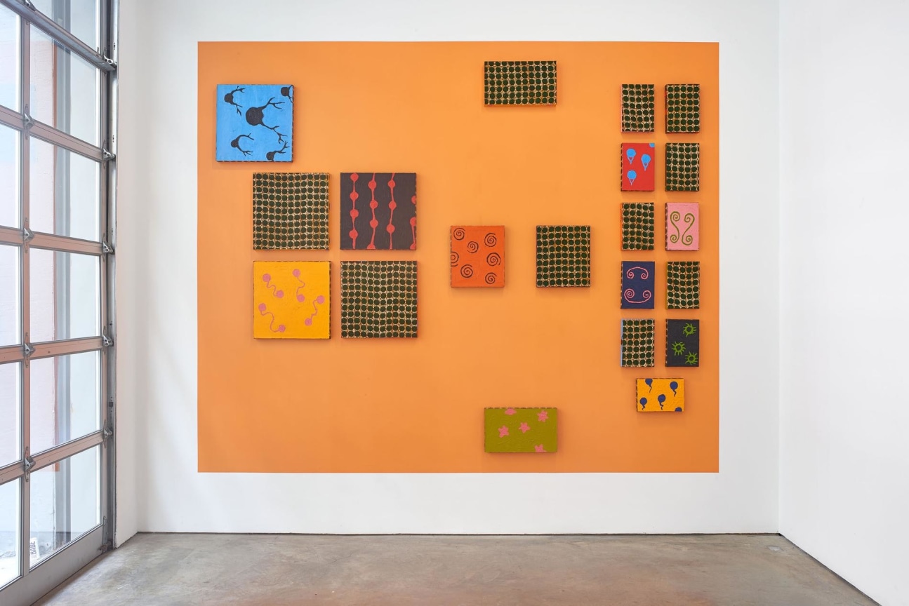 multicolored squares scattered across a bigger orange square painted on the wall