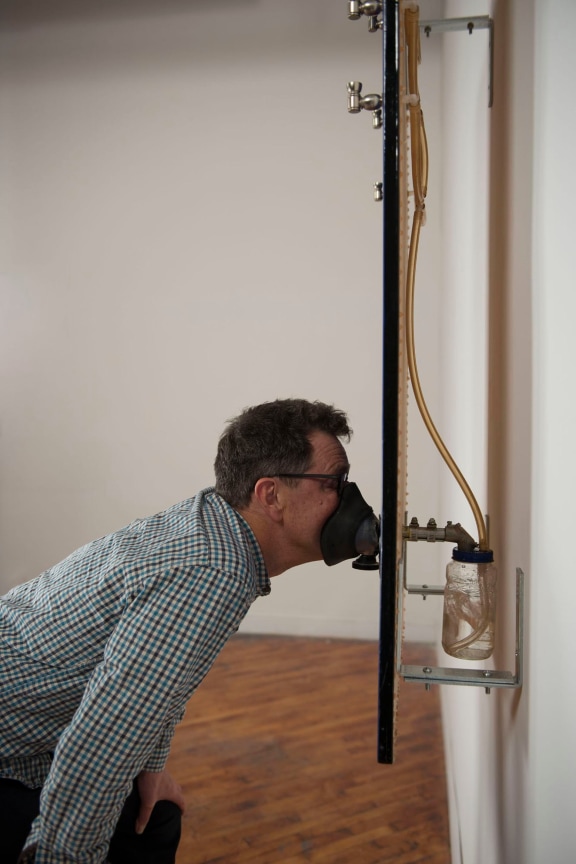 Man in a gas mask attached to an artwork