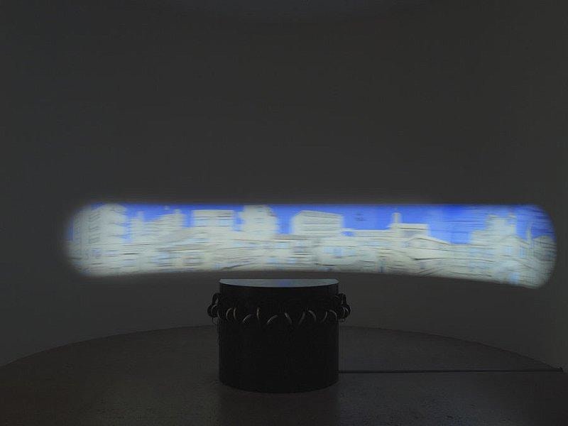 black pedestal in the center of the rom with a limited view of a blurry cityscape behind it