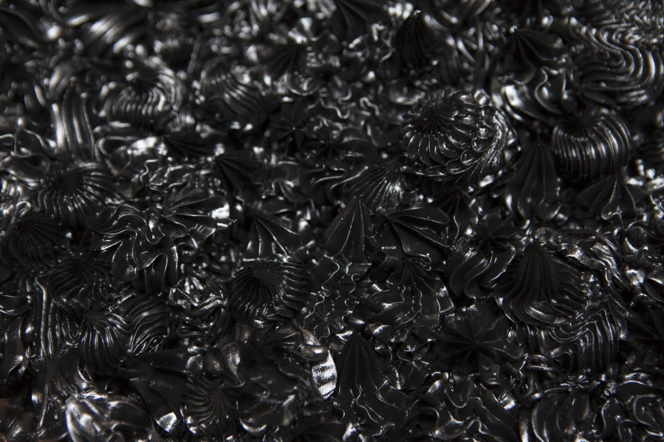 Zoomed in detail of a series of black whipped-cream-like dollops made of oil paint on canvas