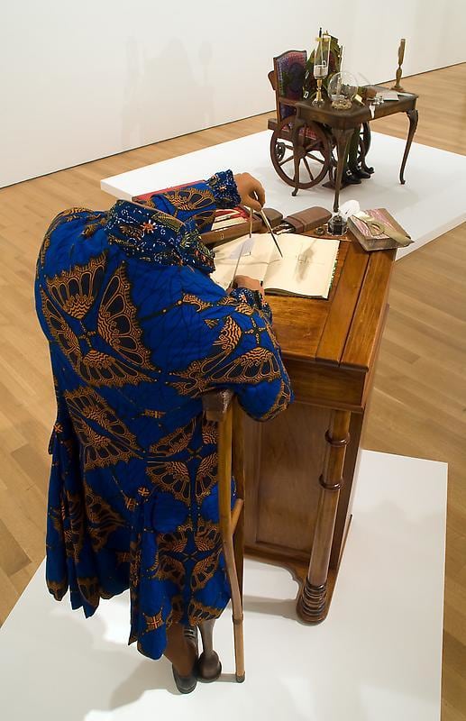 mannequin in a royal blue coat using a compass