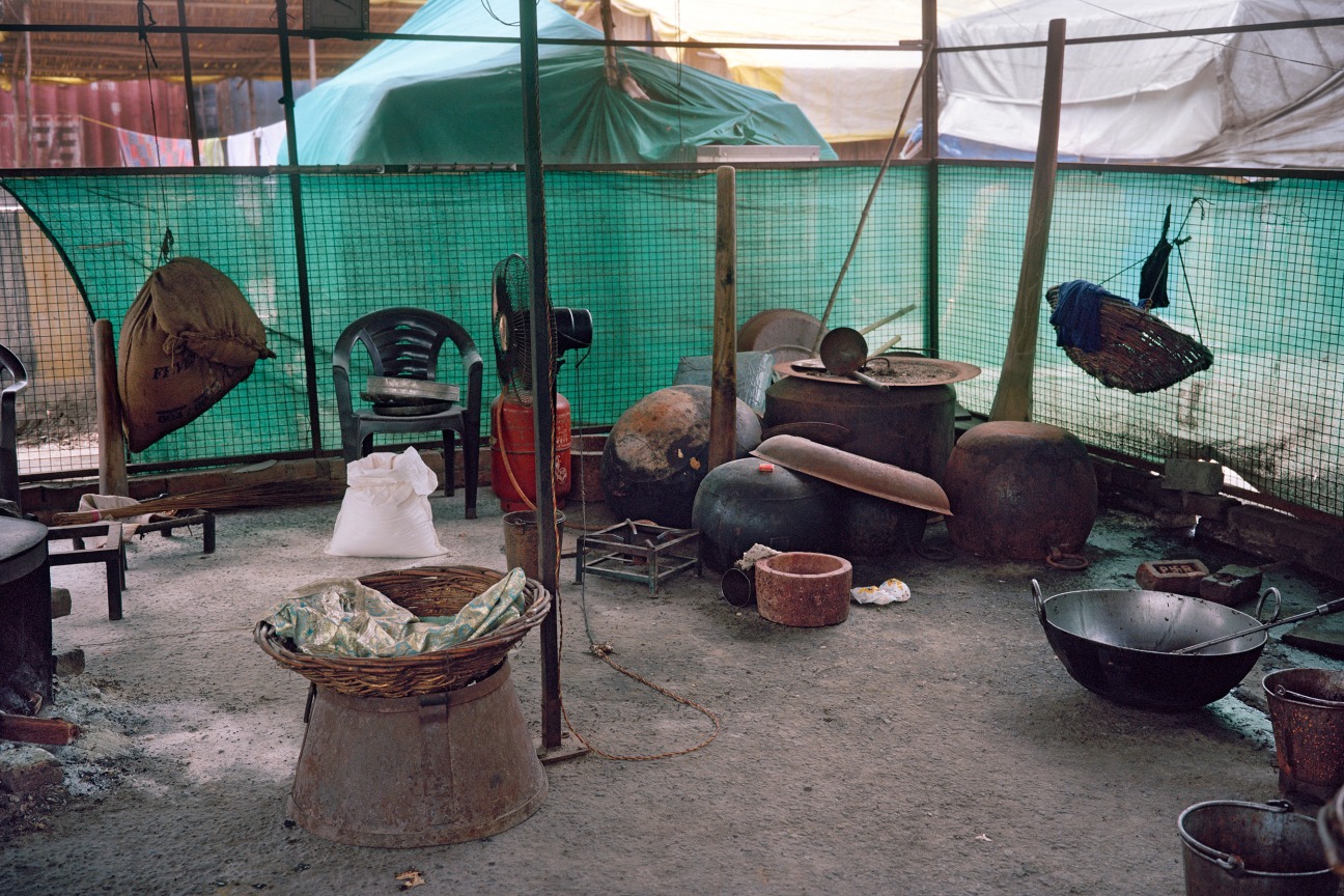 miscellaneous objects sitting on a dirt floor surrounded by a chain fence and a greed drape