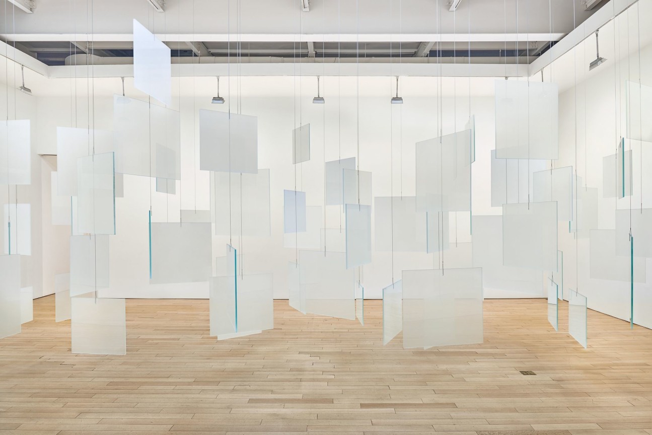 installation view of an artwork composed of glass panels hanging from the ceiling
