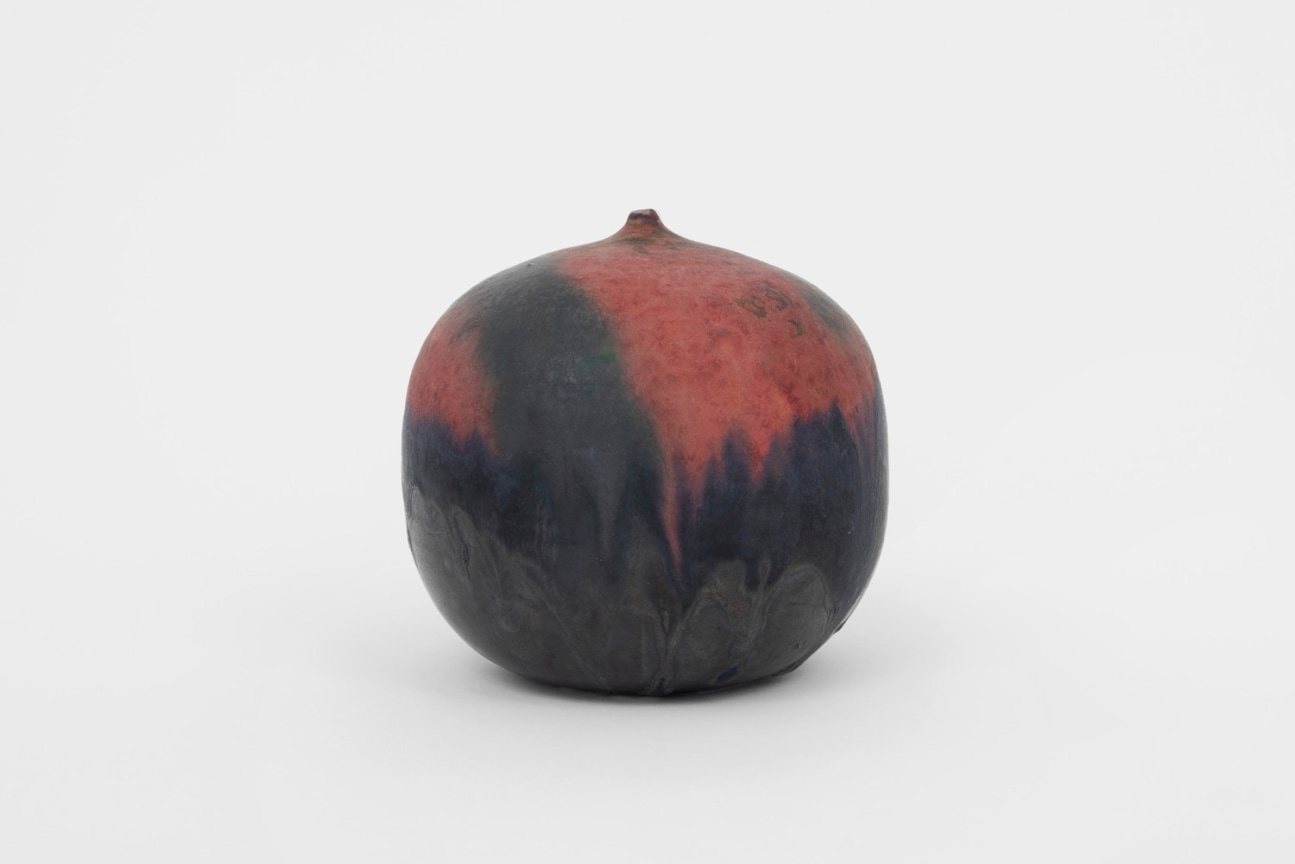 small round ceramic closed form covered in a deep black and red glaze