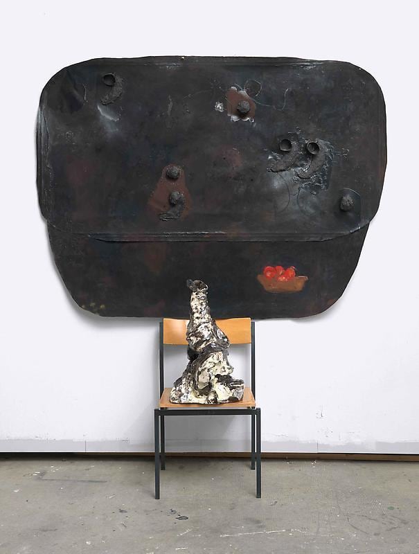 installation with a chair holding a sculpture and a leather-like structure behind it