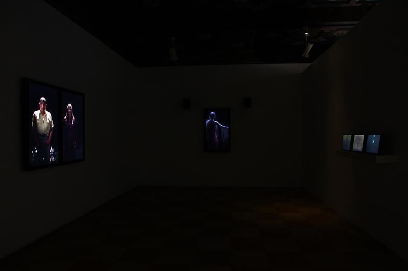 installation view of a dark room with several videos