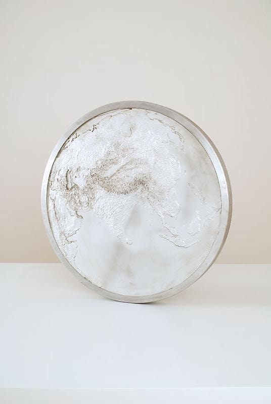 A large aluminum sculpture that resembles a coin