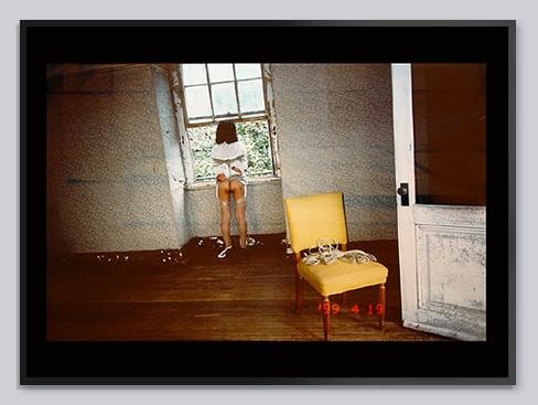 person tied up in erotic bondage looking out the window in an empty room