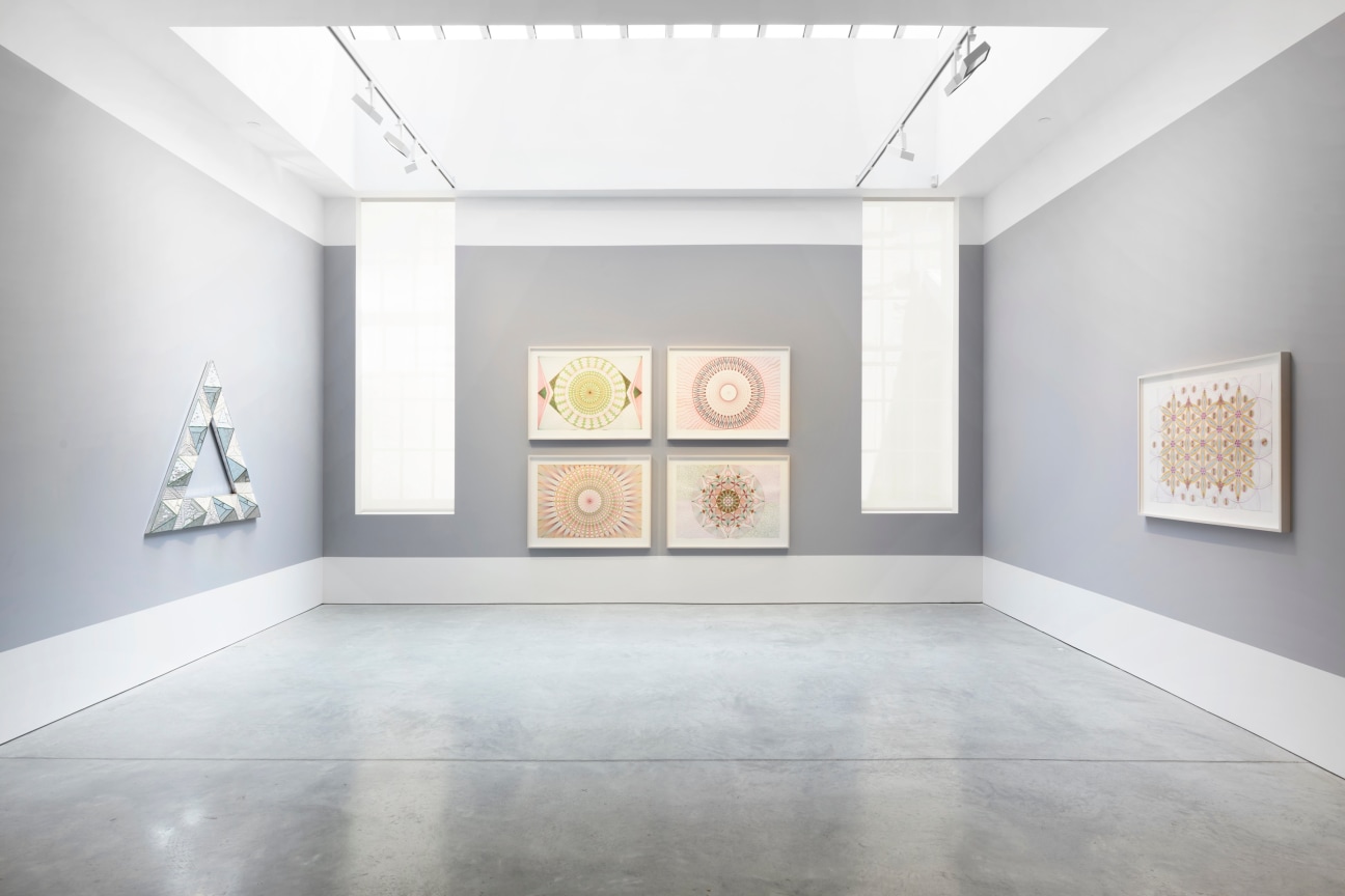 triangular glass artwork next to several other abstract drawings