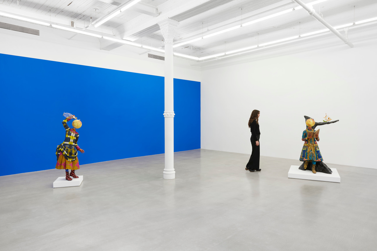 figure walking amongst two elaborately dressed mannequins