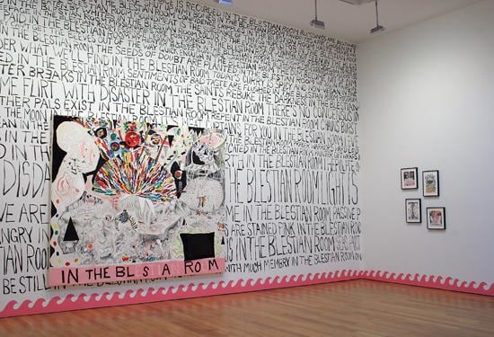 lots of black text written all over one wall with some of Trenton's paintings