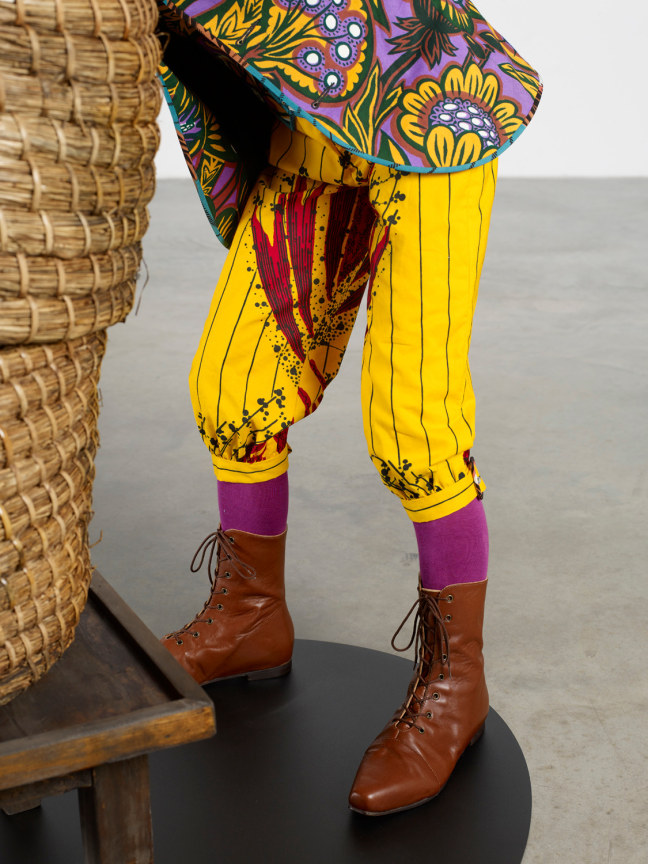 closeup of statue wearing yellow pants, purple socks, and brown shoes