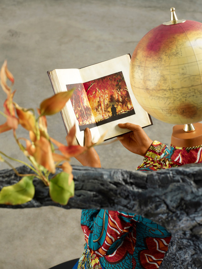 mannequin holding an open book with a picture of a fire