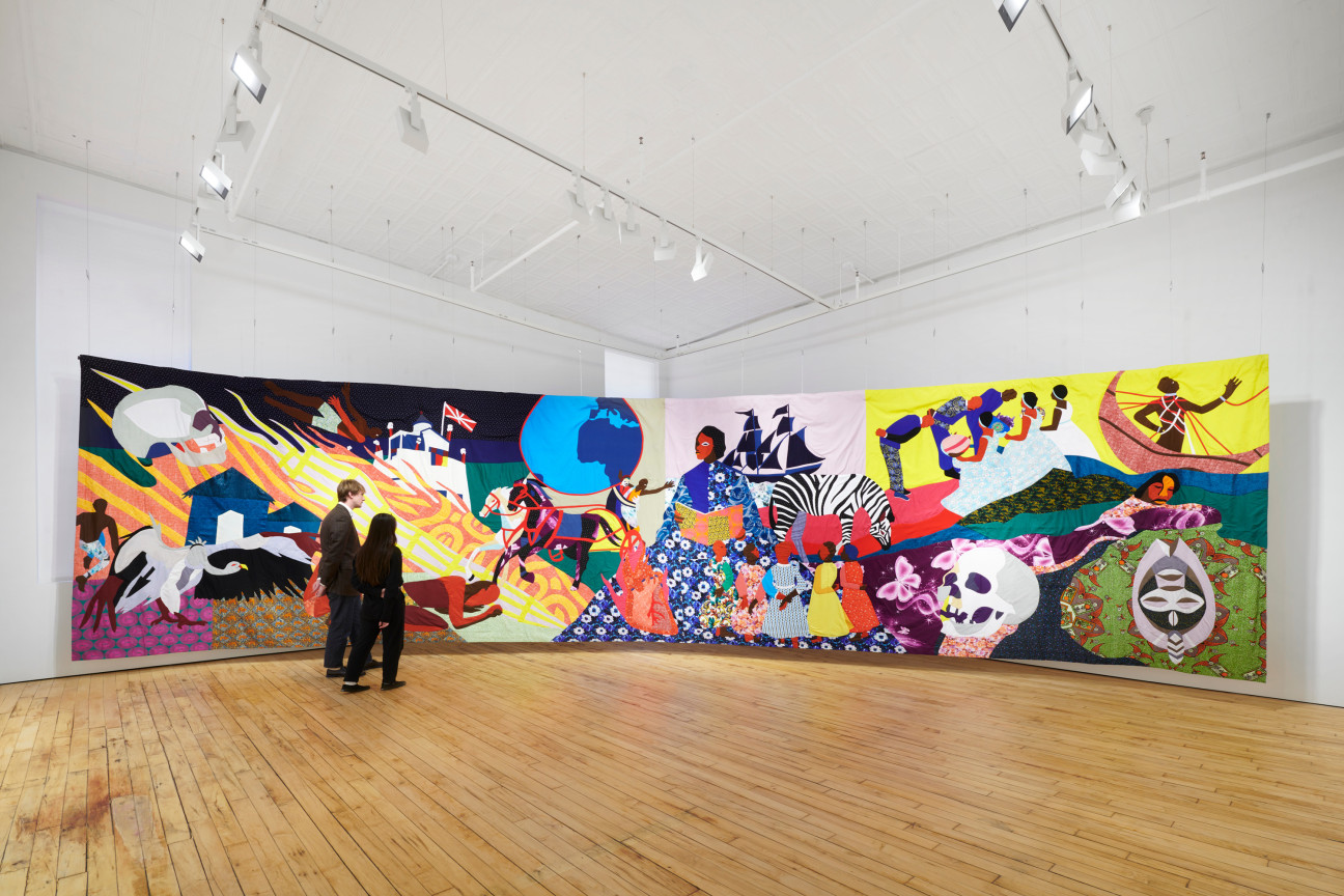 two individuals looking at a large tapestry