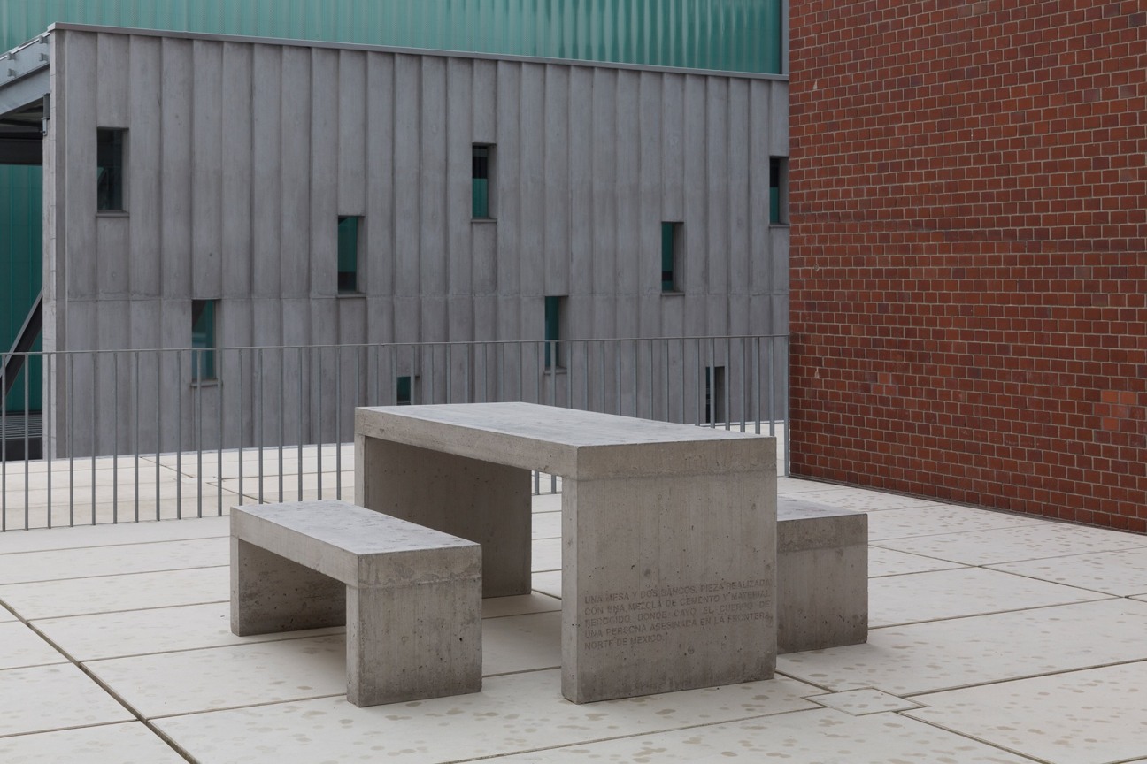 two benches and a table made out of cement; the table has an inscription on the side