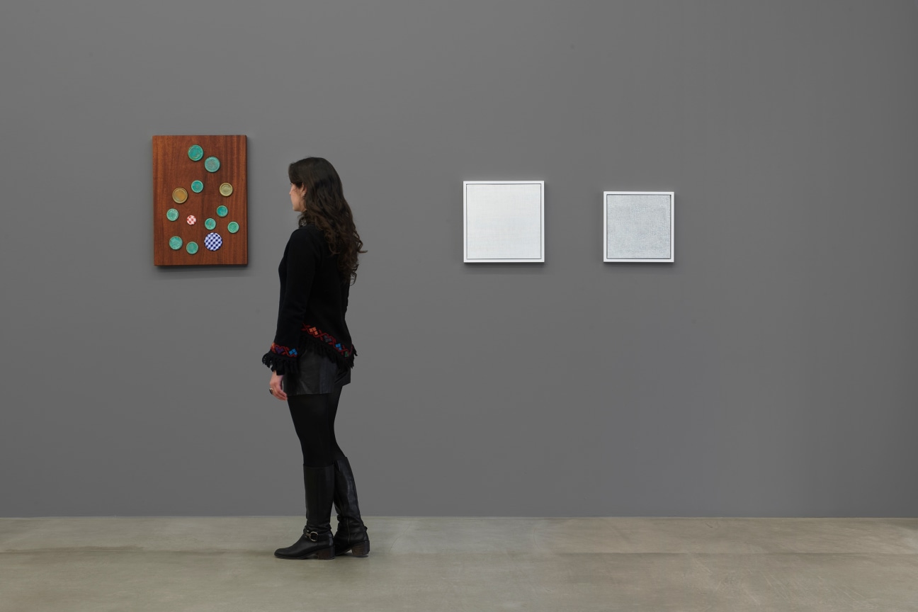 person contemplating an artwork with jam lids