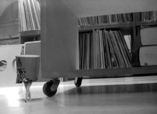tiny tea cup with legs walking next to a book cart