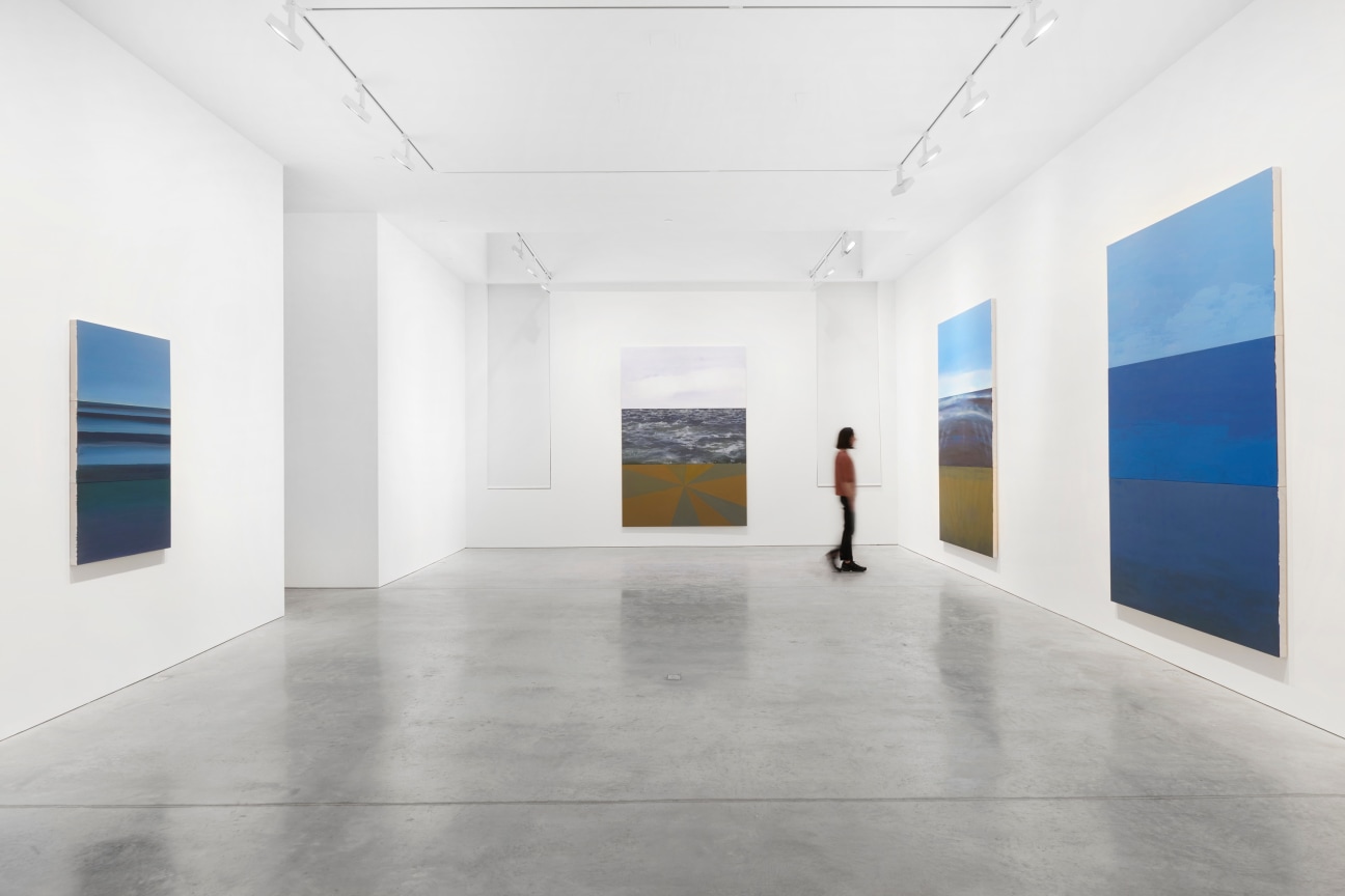 person walking through a gallery full of paintings