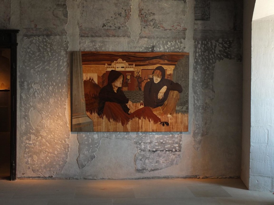 wooden artwork depicting a two individuals sitting in on the grass