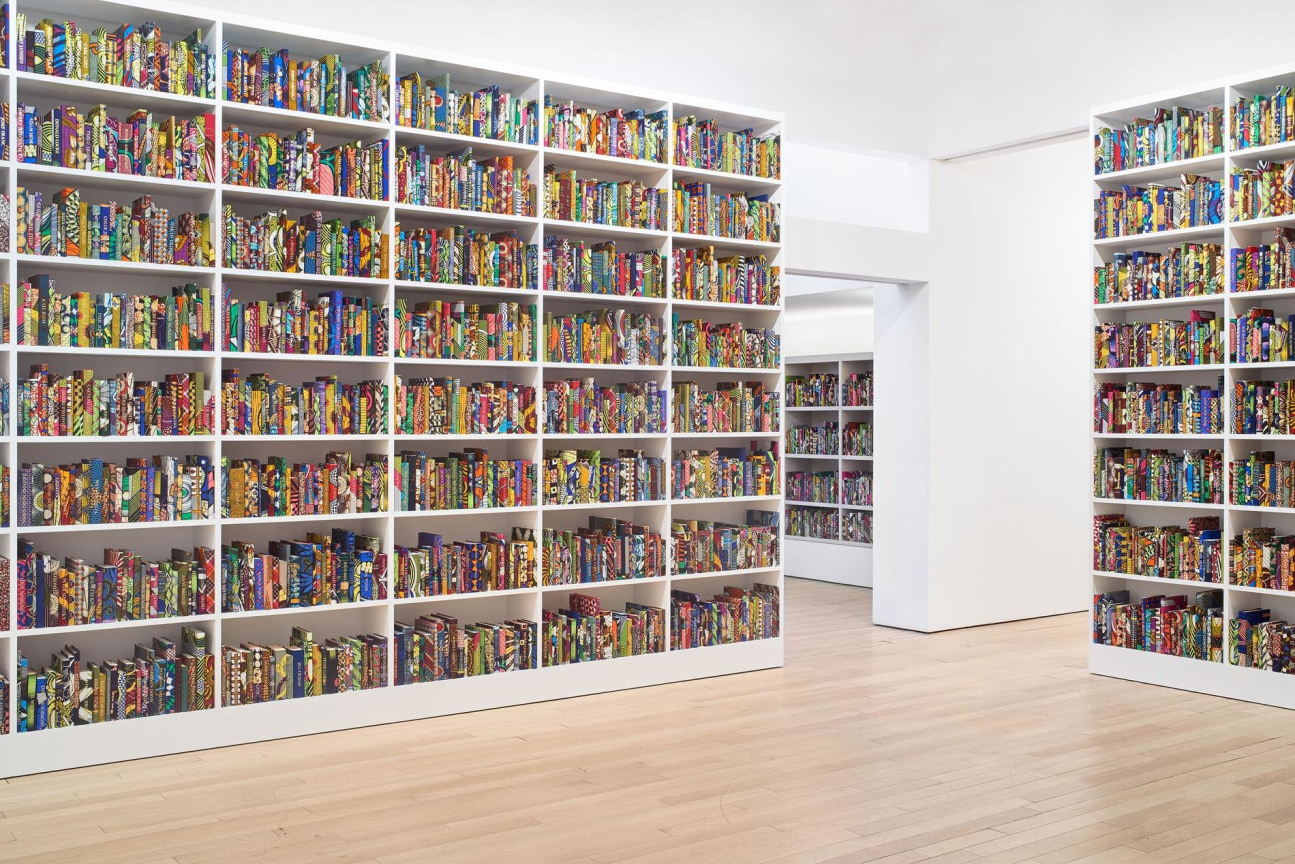 a room full of white bookcases filled with colorful books