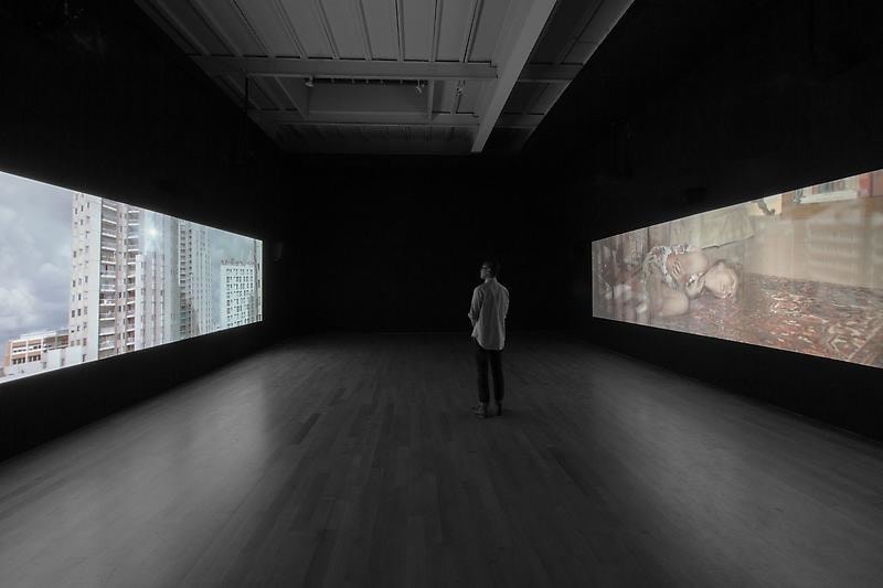 dark gallery with two video projections on opposite sides