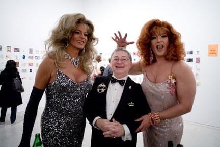 two female presenting individuals with a well-dressed man in the middle