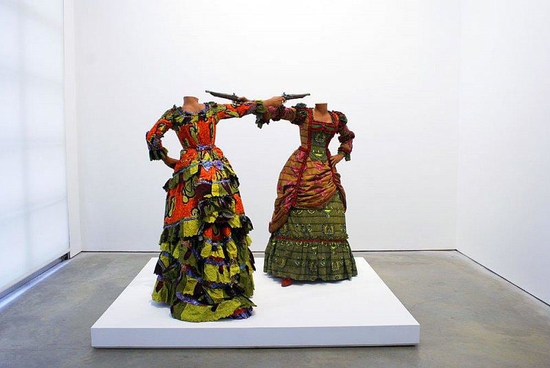 headless mannequins pointing guns at each other