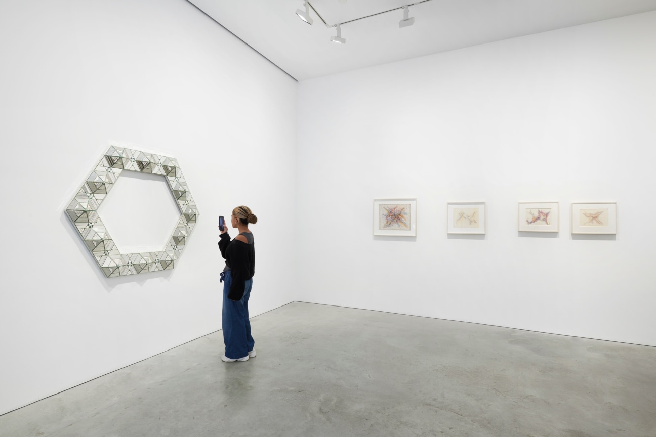 person taking a photograph of a hexagonal glass work with their smart phone