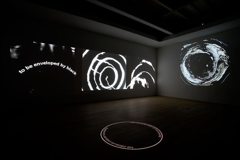 installation view of dark room with video projections