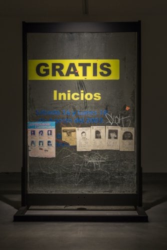 glass panels containing missing persons posters, some graffiti, and the word GRATIS on the top