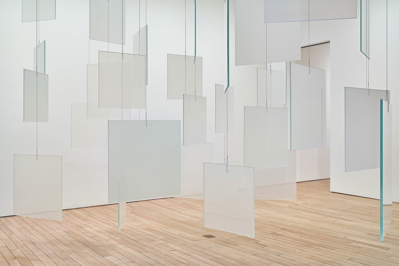 installation view of an artwork composed of glass panels hanging from the ceiling