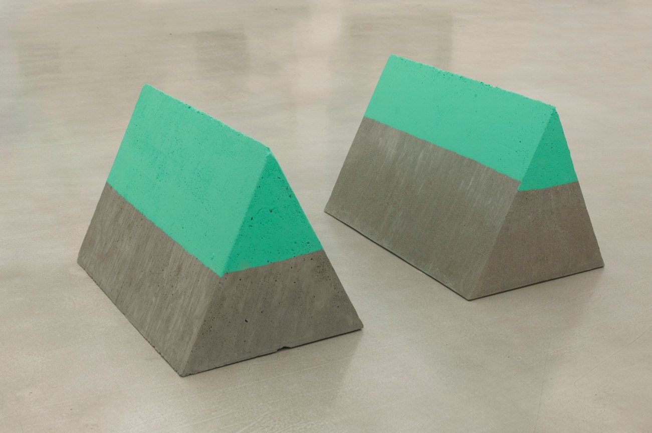 two triangular-shaped slabs of concrete with their upermost part painted in a greenish tone