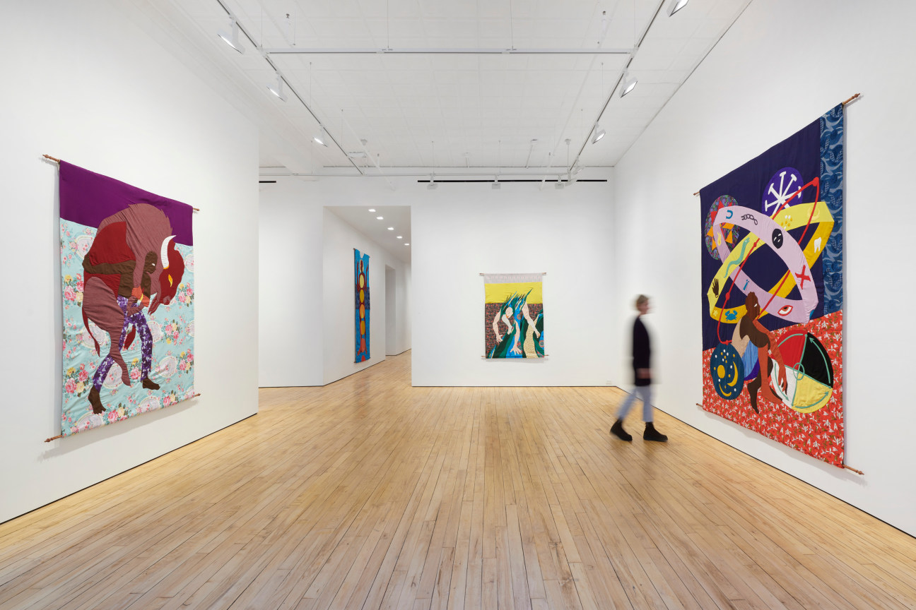 person walking through a gallery with tapestries