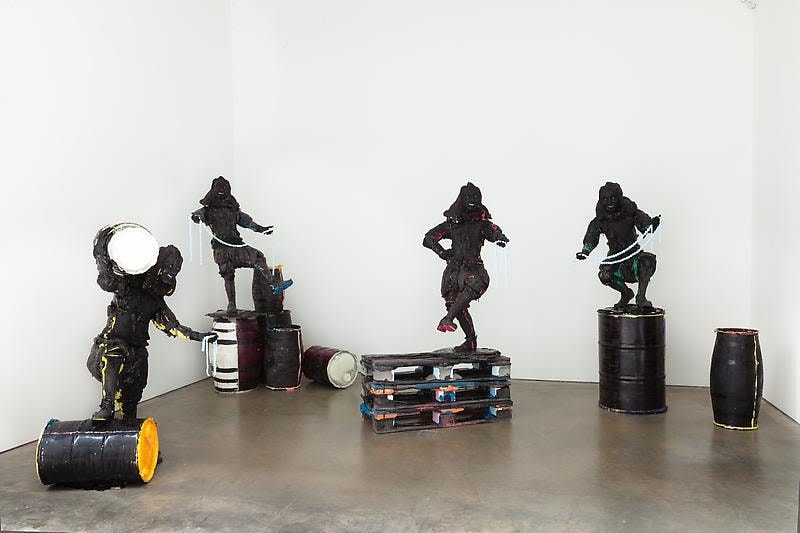 instalation view of black figures balancing themselves on different objects