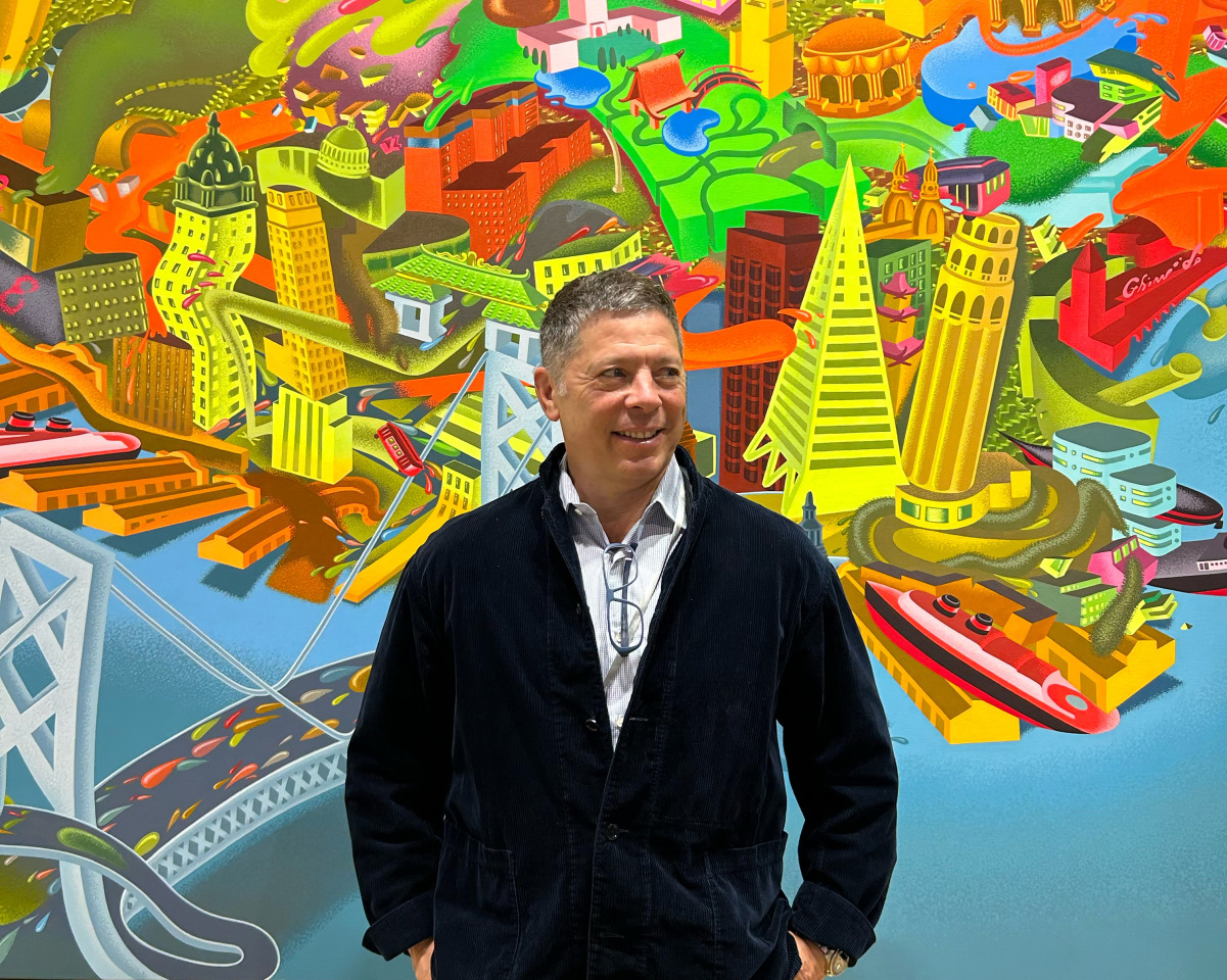 Portrait of Adam Lindemann standing in front of Peter Saul&rsquo;s&nbsp;View of San Francisco&nbsp;(1979). &copy; 2025 Peter Saul/Artists Rights Society (ARS), New York. Courtesy of the artist, and Venus Over Manhattan, New York.