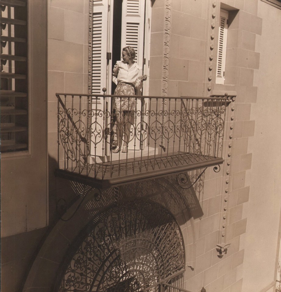 Louise Dahl-Wolfe, Morning in Havana, 1941. A model stands in the doorway to a balcony, looking back into the interior.