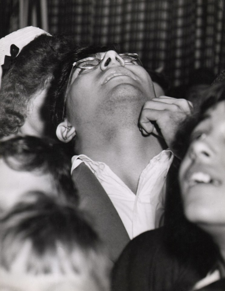 03. Weegee, Untitled (Man looking to see where plane crashed into Empire State Building), ​1945. Central man in a crowd tilts his head back to gaze directly upward.