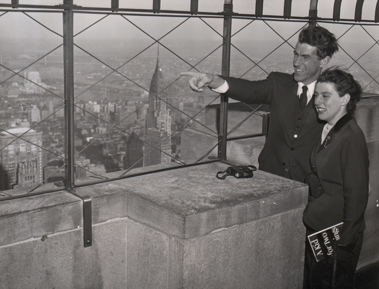 14. Sam Schulman, Mt. Everest conqueror Sir Edmund Hillary &amp; Lady Hillary, ​1954. A man and woman stand on the right of the frame, both smiling and looking toward the left of the frame. The man is also pointing to the left.