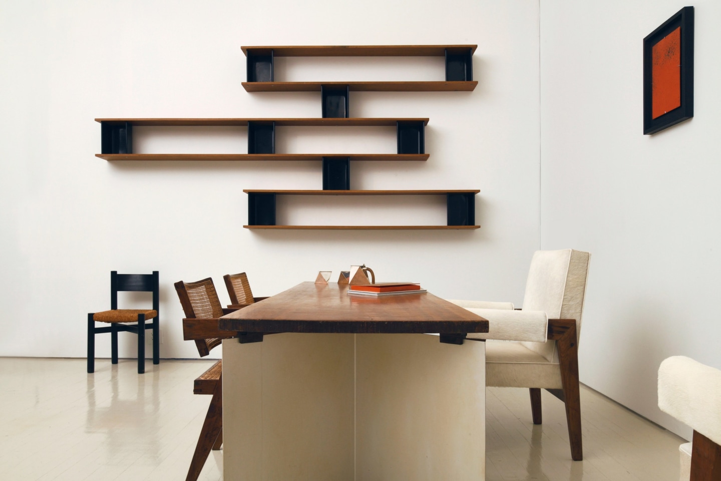 Alyssa Kapito's room | Pieces from left to right are Charlotte Perriand's Meribel chair (c. 1950), Charlotte Perriand's &quot;Nuage&quot; wall shelving (c. 1950), Pierre Jeanneret's pair of office chairs (c. 1955-56), Jean Paul Barray's table titled &quot;Hommage &agrave; Le Corbusier - Chandigarh&quot; (1965), Gabriele De Vecchi's sculptural coffee and tea set (c. 1980), Le Corbusier, Pierre Jeanneret &amp; Jeet Lal Malhotra's &quot;Advocate and Press&quot; armchairs (1954-55), and Pierre Sabatier's &quot;M&eacute;tal Rouge&quot; wall sculpture (1980)