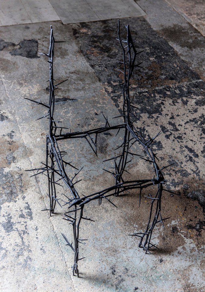 Michele Oka Doner's Terrible Chair, full diagonal view from above in a darker warehouse setting