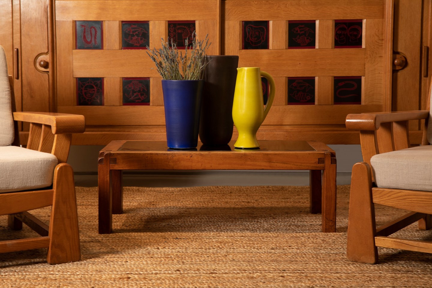 Close up installation image from the exhibition. Pieces from the left from right are Maison Regain's pair of armchairs, Guillerme et Chambron's sideboard, Pierre Chapo's &quot;T18&quot; coffee table, Suzanne Ramie's ceramic vases, and Pol Chambost's ceramic pitcher