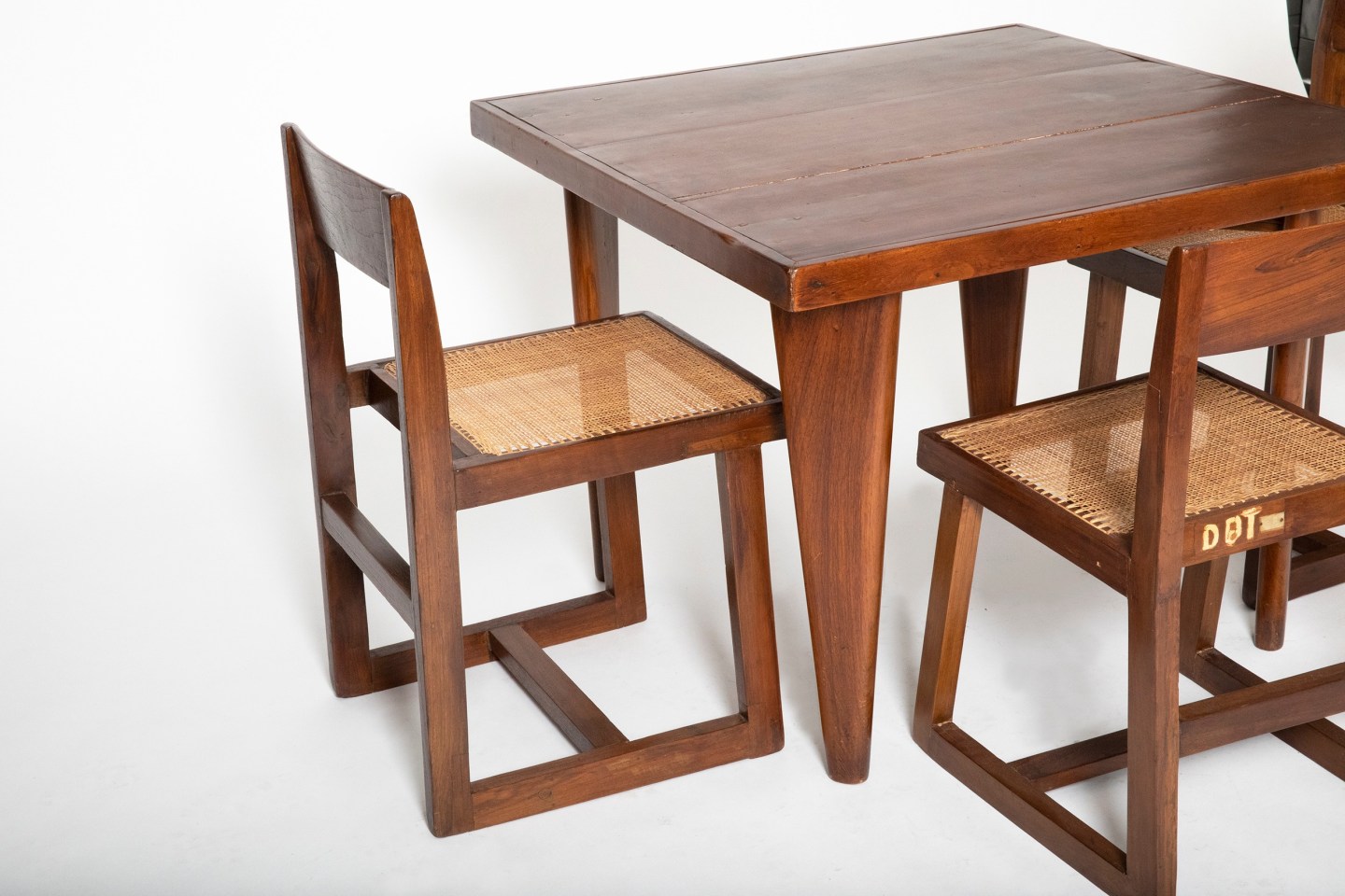Close up view of Pierre Jeanneret's square table shown with set of 4 Jeanneret chairs