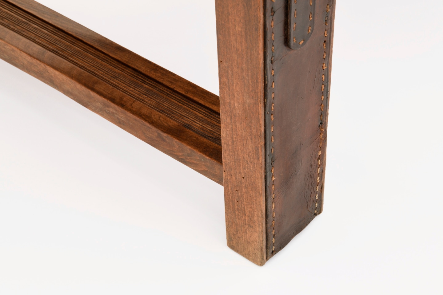 Jacques Adnet's coffee table/bench detailed view of leather and wood of leg