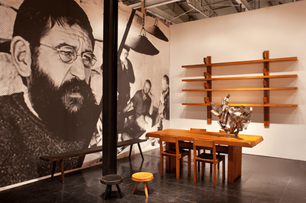 Magen H Gallery's booth at Collective Design Fair, showcasing Pierre Chapo's B17 Longue bookshelf, &quot;T14C&quot; dining table and a set of &quot;S24B&quot;chairs, Albert Feraud's sculpture, Charlotte Perriand's low stools, and Marolles' bench
