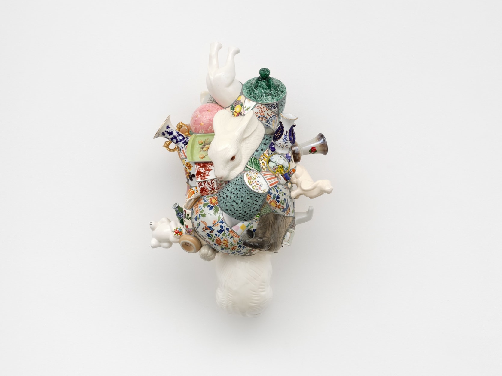 A composite ceramic sculpture made from fragments of animal figurines and vases mounted to the wall. 