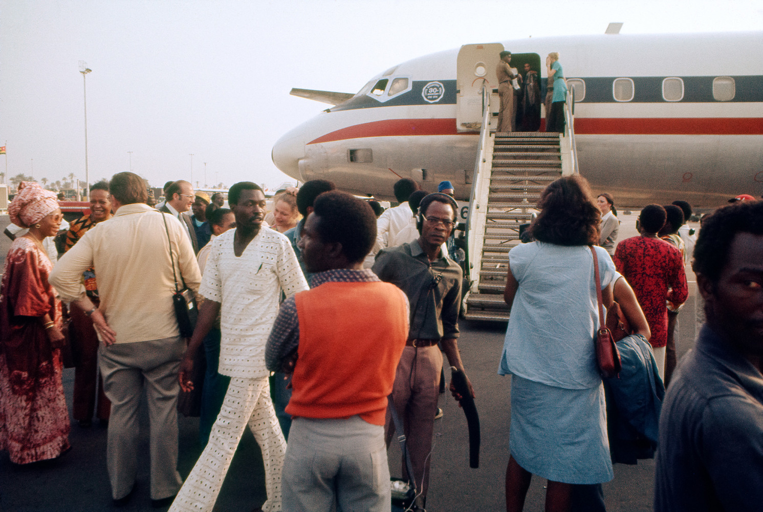 Roy Lewis (b. 1937)
U.S.A. Participants &amp;quot;Arrive at Lagos Airport&amp;quot;, 1977
Archival inkjet print on Simply Elegant Gold Fibre paper
Image: 13 3/4 x 20 inches (34.9 x 50.8 cm) Sheet: 17 x 22 inches (43.2 x 55.9 cm)
Framed: 18 5/8 &amp;times; 25 3/8 &amp;times; 1 1/2 inches (47.3 &amp;times; 64.5 &amp;times; 3.8 cm)
Edition of 5, printed 2023