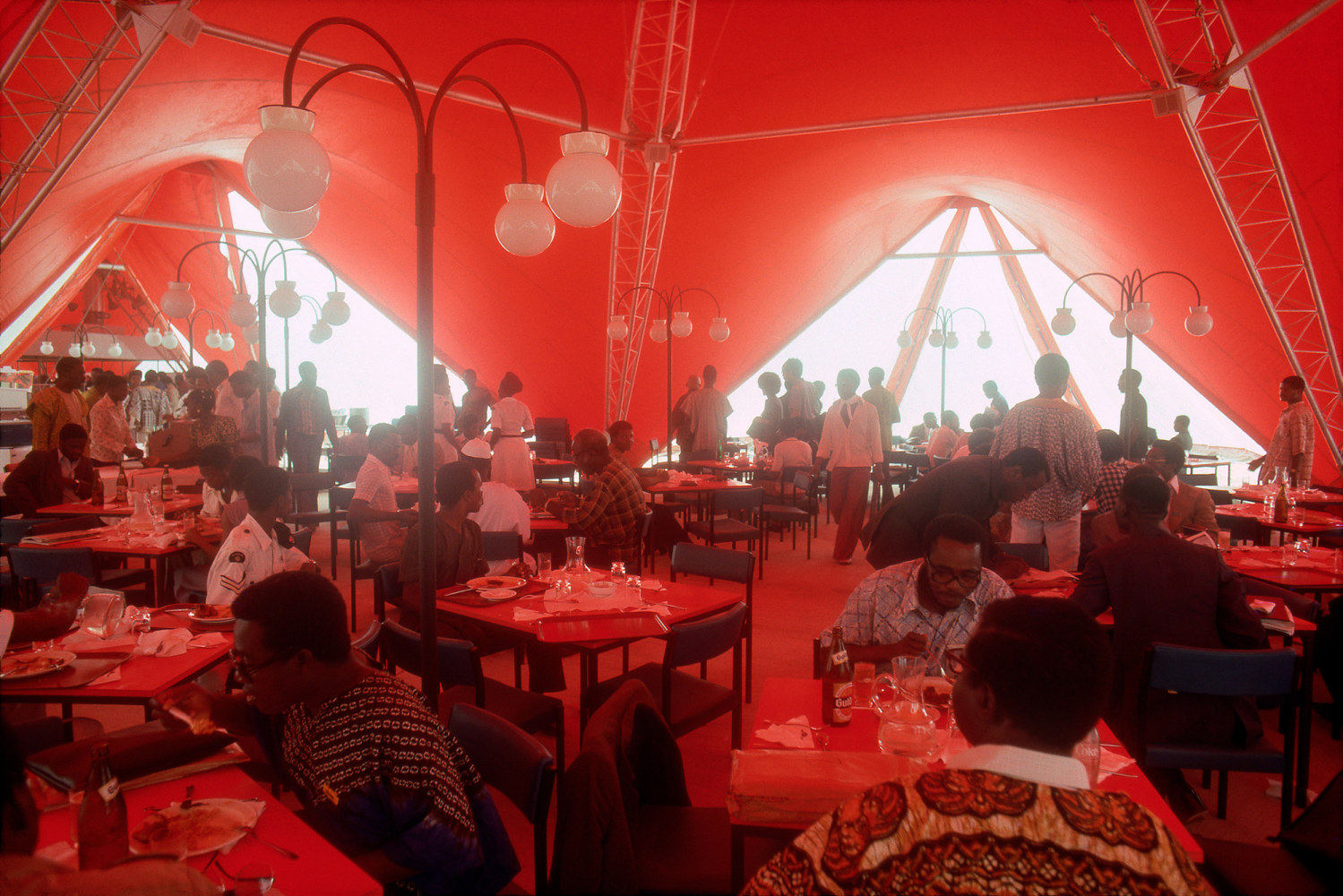 Roy Lewis (b. 1937)
National Theater Meal Tents in Lagos, 1977
Archival inkjet print on Simply Elegant Gold Fibre paper
Image: 13 3/4 x 20 inches (34.9 x 50.8 cm) Sheet: 17 x 22 inches (43.2 x 55.9 cm)
Framed: 18 5/8 &amp;times; 25 3/8 &amp;times; 1 1/2 inches (47.3 &amp;times; 64.5 &amp;times; 3.8 cm)
Edition of 5, printed 2023
