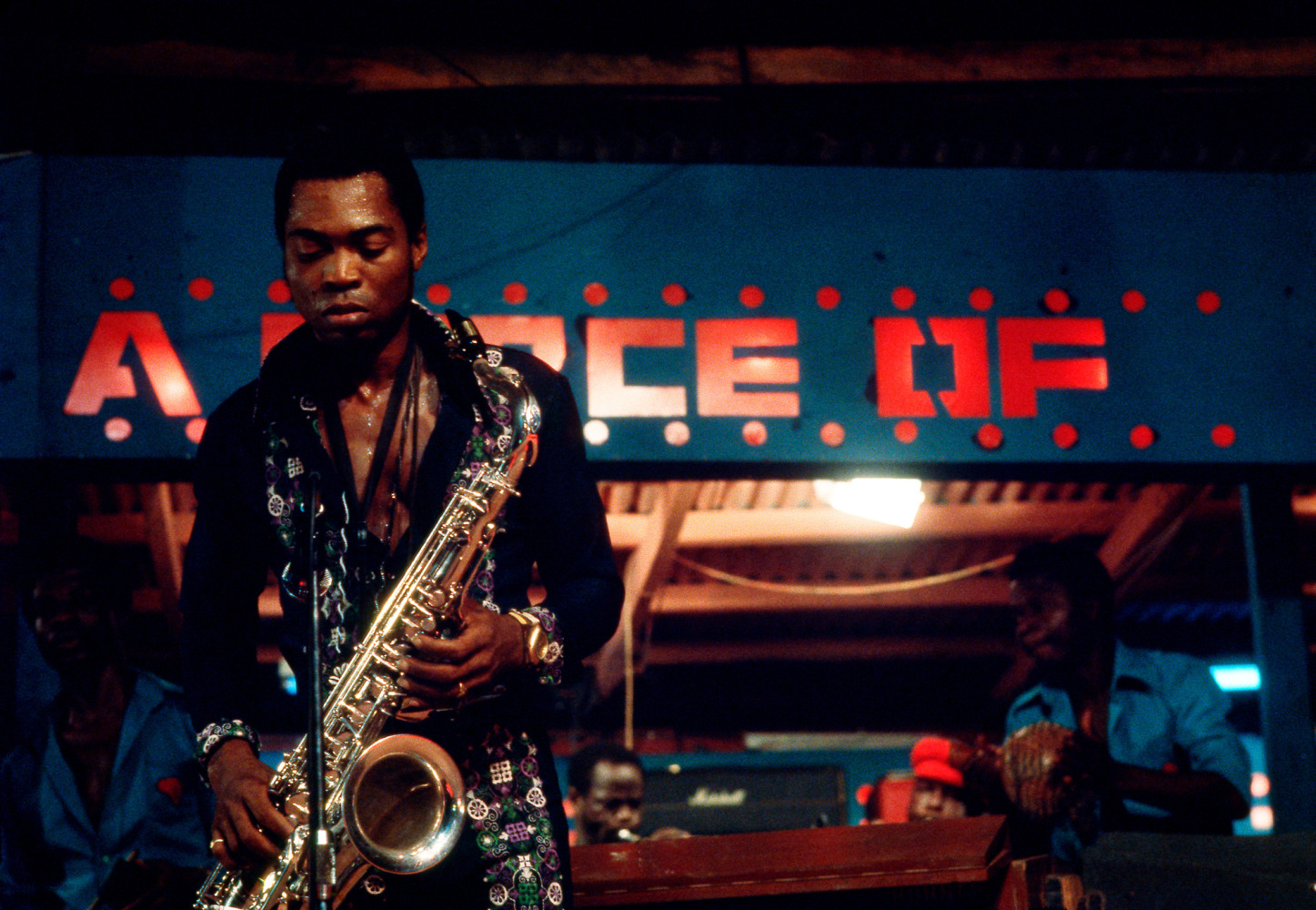 Roy Lewis (b. 1937)
Fela and his Sax at his Shrine Nightclub, 1977
Archival inkjet print on Simply Elegant Gold Fibre paper
Image: 13 3/4 x 20 inches (34.9 x 50.8 cm) Sheet: 17 x 22 inches (43.2 x 55.9 cm)
Framed: 18 5/8 &amp;times; 25 3/8 &amp;times; 1 1/2 inches (47.3 &amp;times; 64.5 &amp;times; 3.8 cm)
Edition of 5, printed 2023