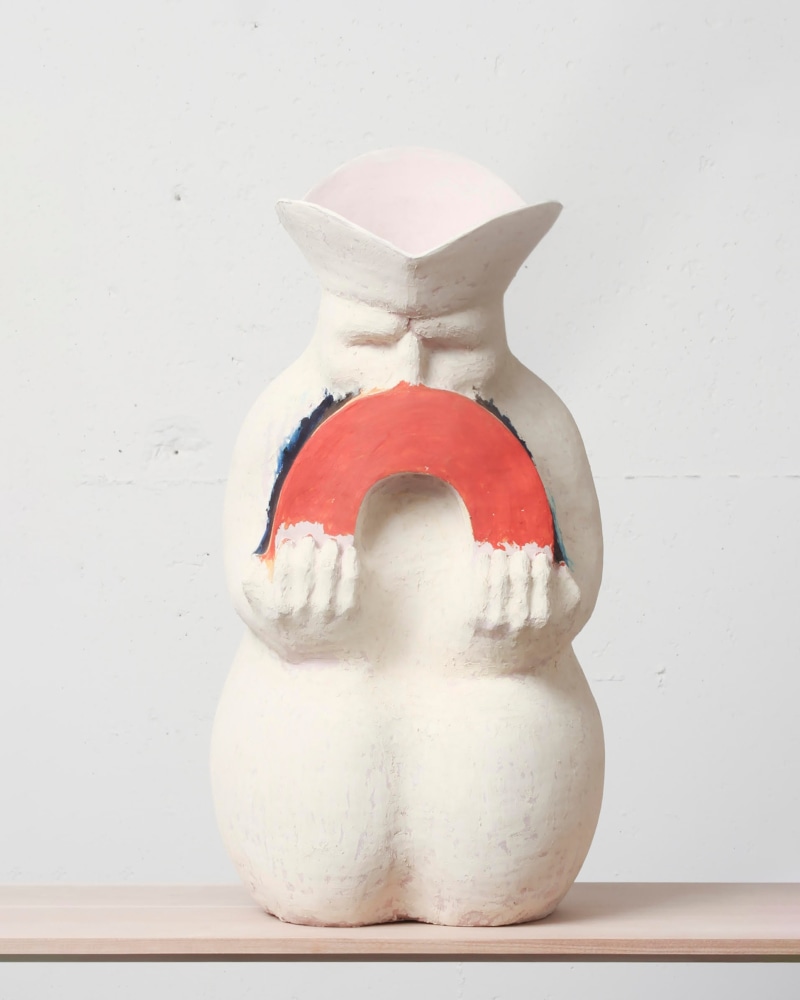 A hollow white ceramic sculpture of a man holding a rainbow.