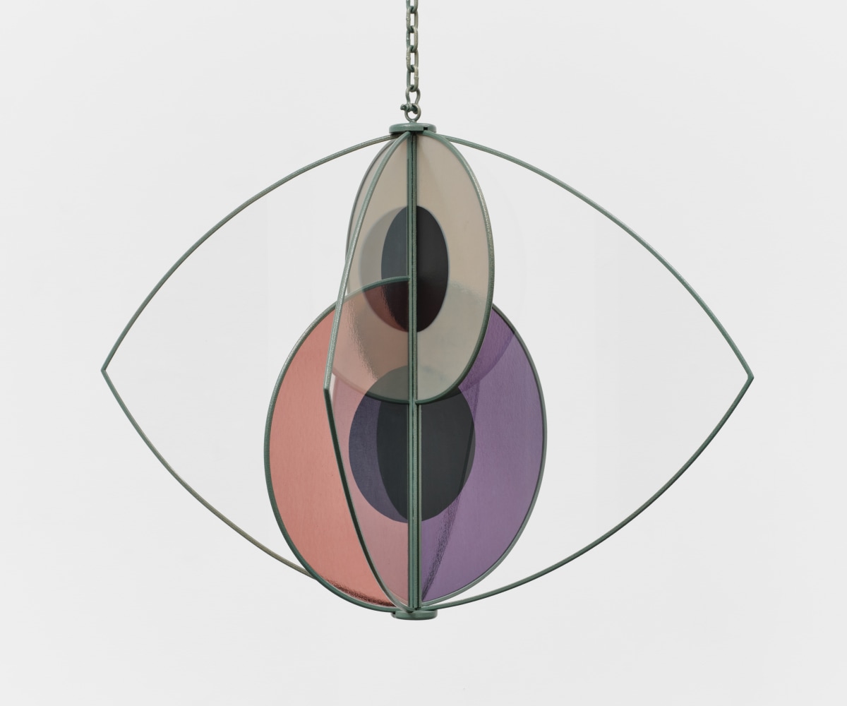 A hanging sculpture with two interlocking glass iris' inside a metal eye frame.